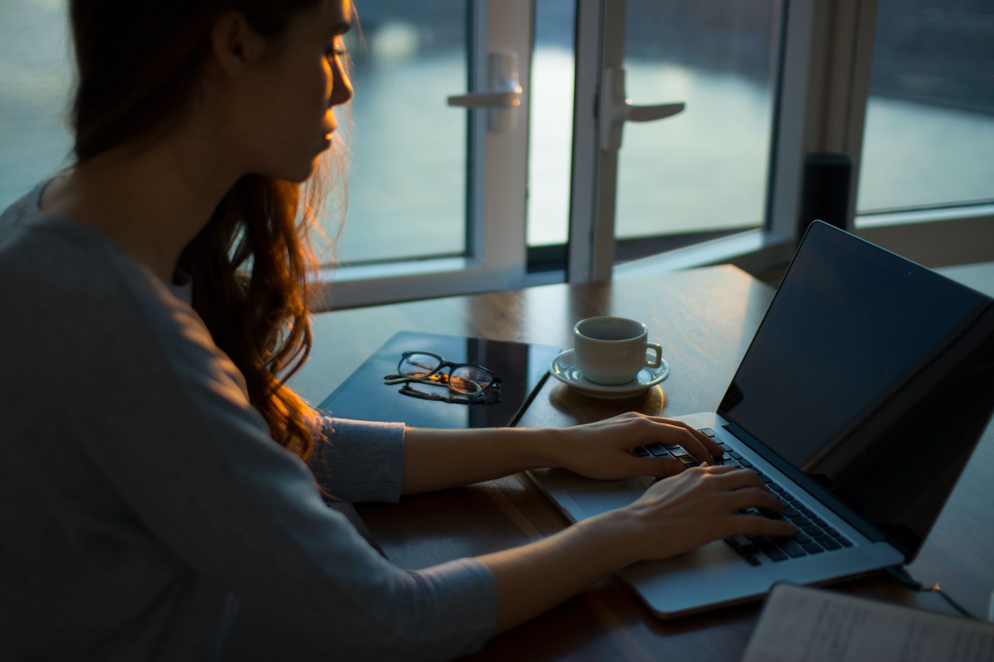 Woman using a laptop beside a window at home
