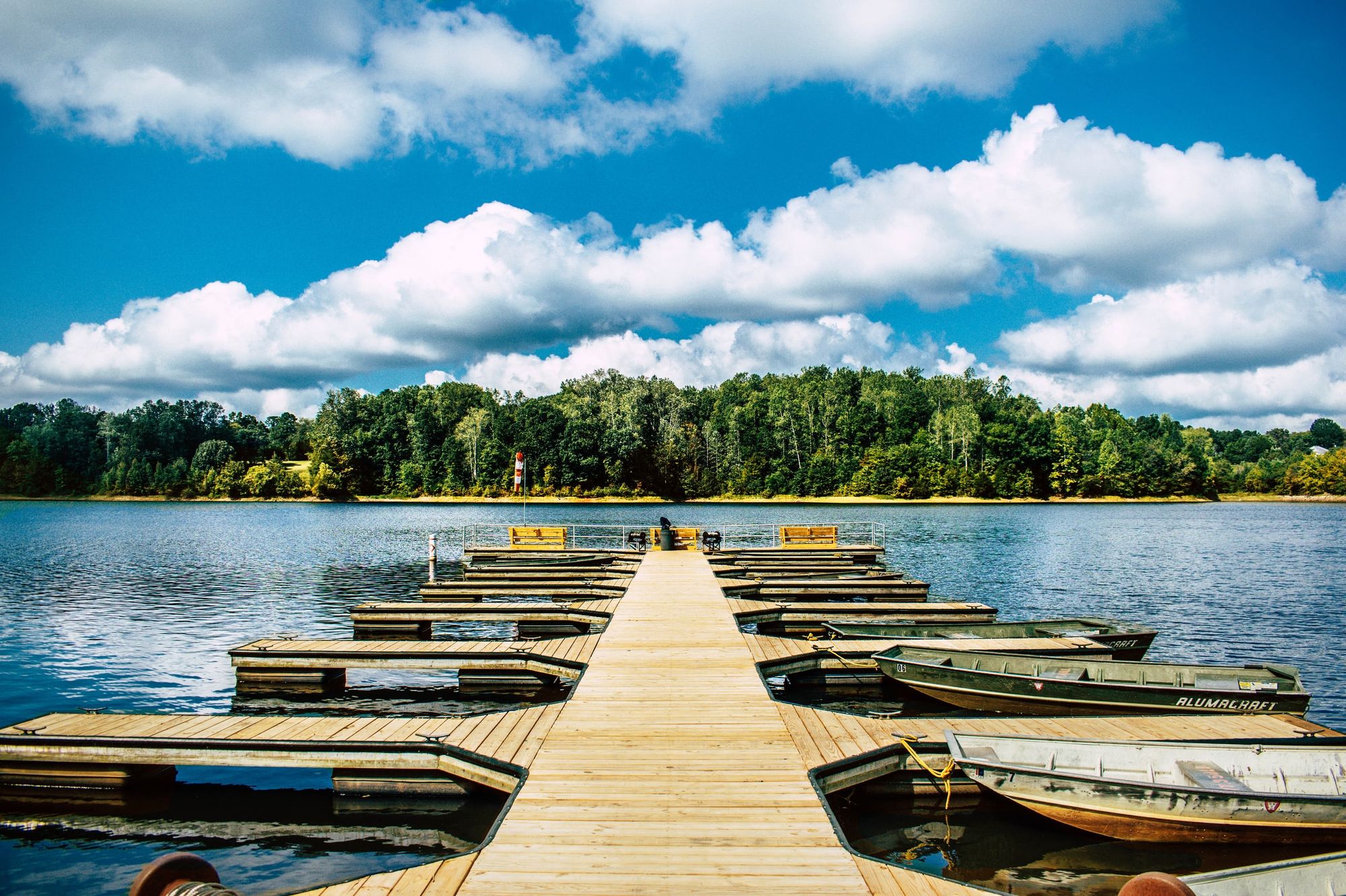Wooden dock and small boats on a lake surrounded by trees