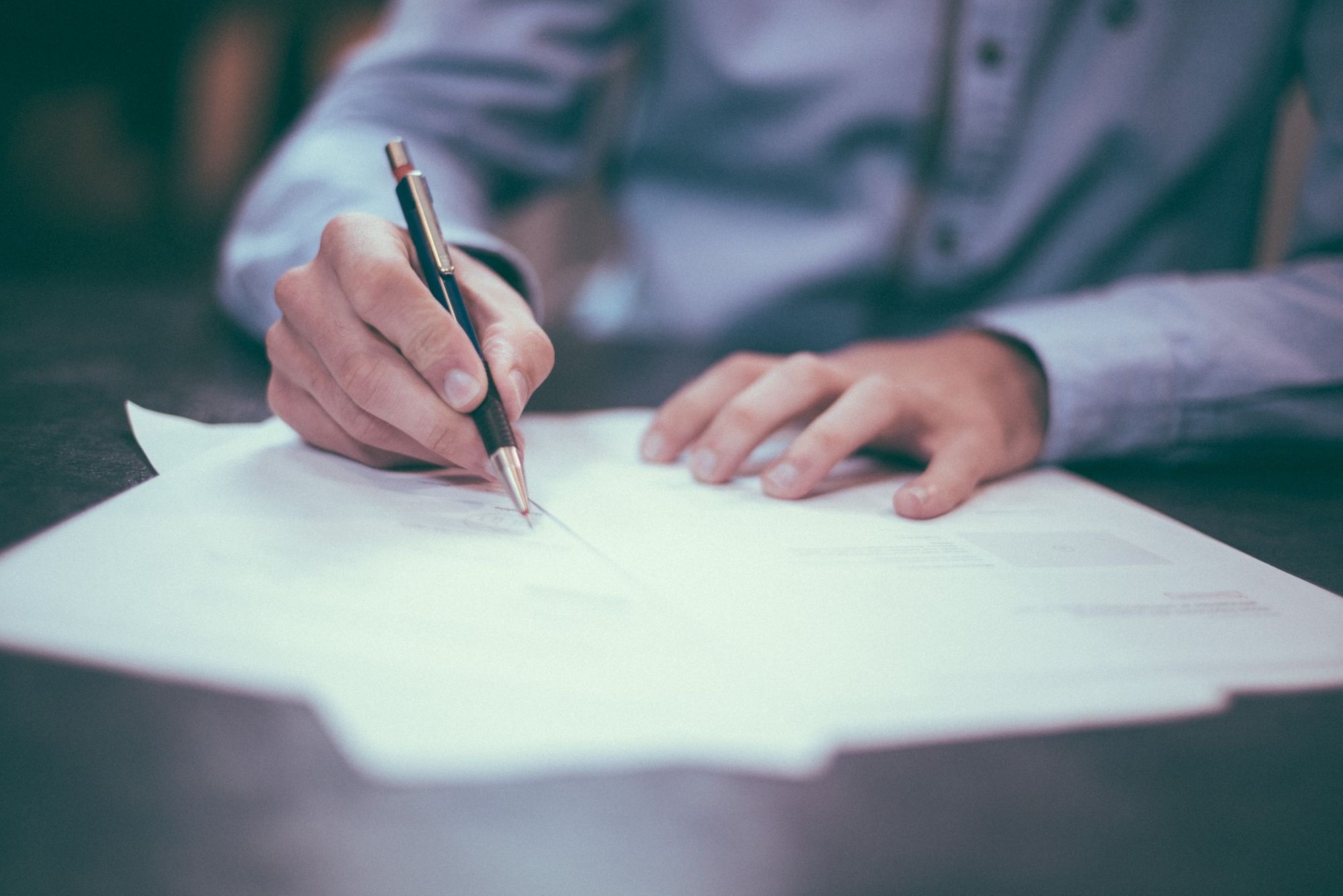 Person signing a document on a desk