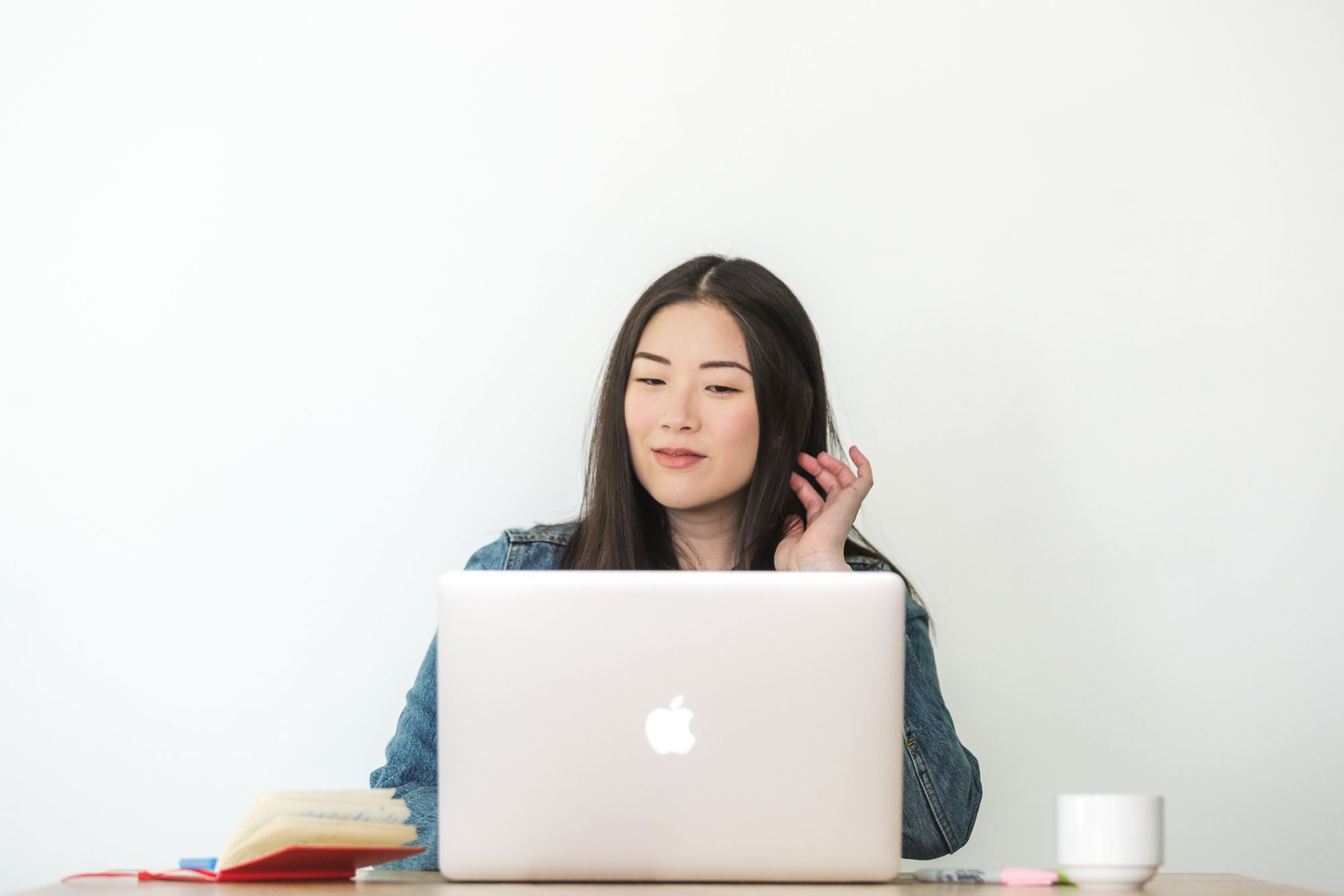 Woman working on a laptop against a white wall
