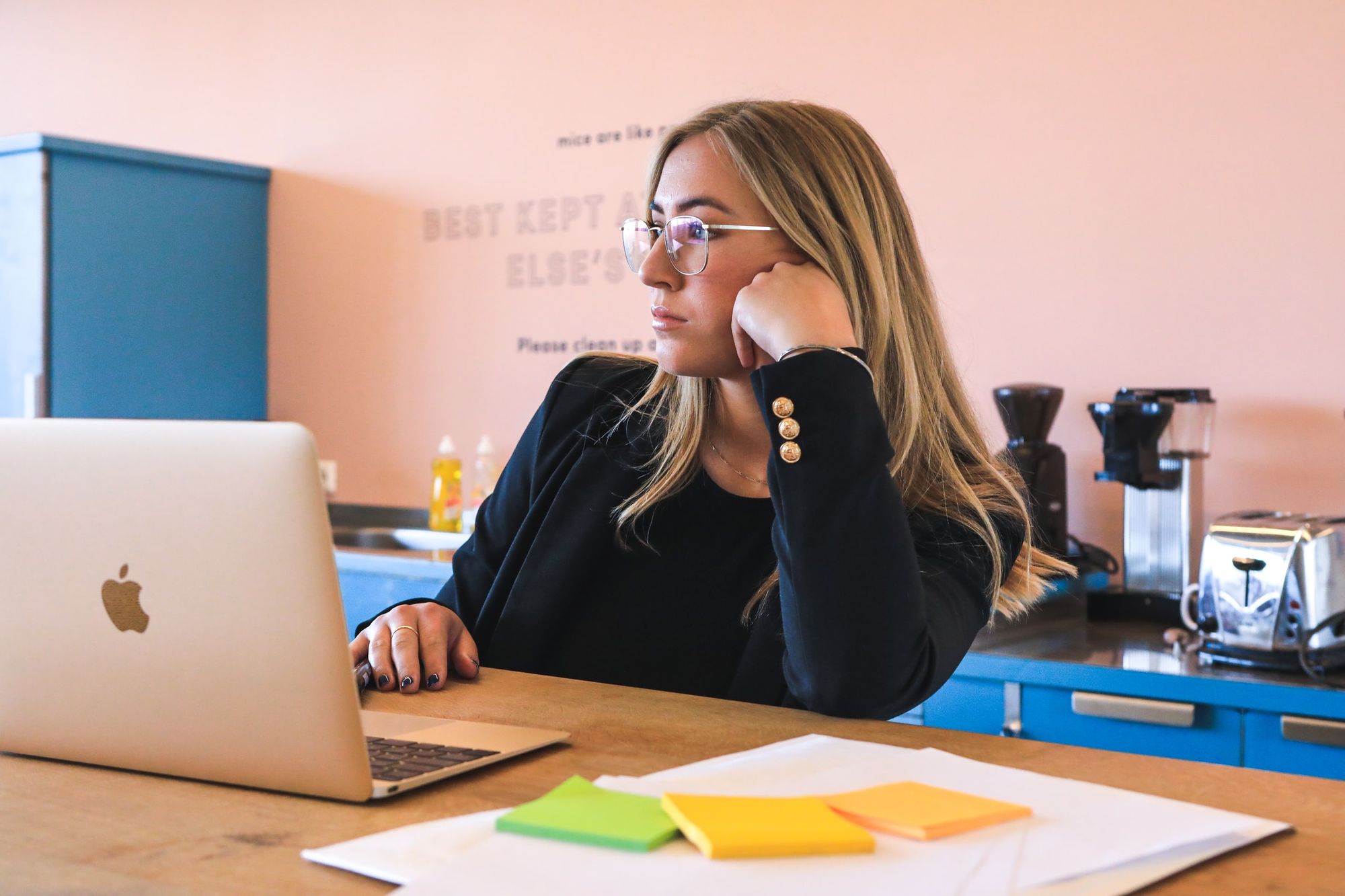 Woman considering information on a laptop beside a cup of coffee